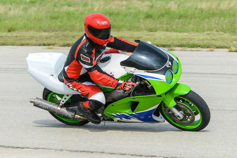 Green and white sportbike with rider in red and black leathers on a track