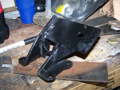 1988 Suzuki Samurai - Engine mount bracket, likely for a custom swap, sits on a workbench with tools nearby.