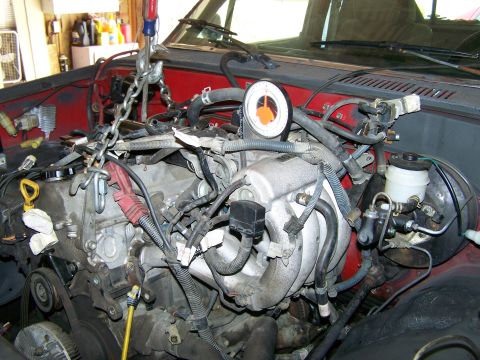 1988 Suzuki Samurai - The engine is being removed from the vehicle using a hoist, with a gauge attached to monitor pressure.