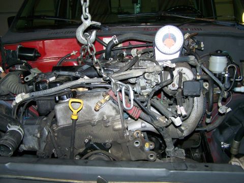 1988 Suzuki Samurai - Engine being removed or installed with a chain hoist and a dial indicator tool.