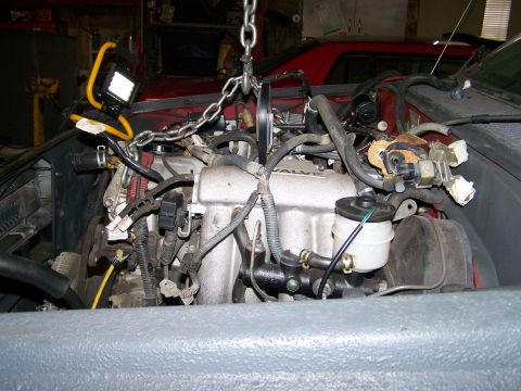 1988 Suzuki Samurai - Engine bay during removal, showing the engine suspended by a chain hoist.