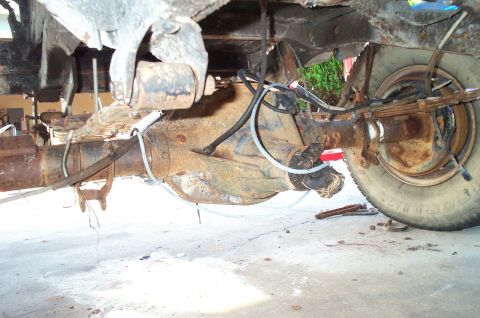 1995 Ford Bronco - Close-up view of a vehicle's rear axle and suspension system, highlighting its aged and rusty condition.