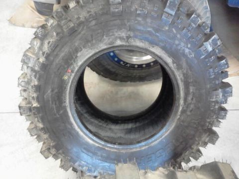1995 Ford Bronco - A close-up view of a single, aggressive off-road tire, with another tire and wheel partially visible within its opening.