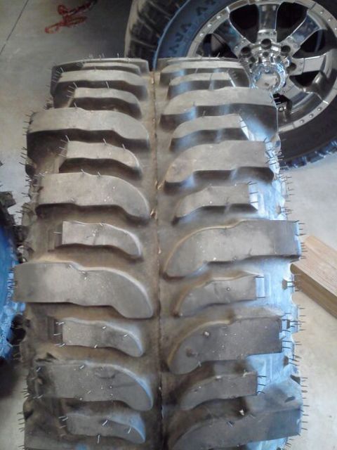 1995 Ford Bronco - Close-up of two large off-road tires and a chrome wheel, suggesting off-road capability.