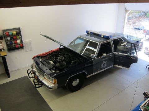 1991 Ford LTD Crown Victoria - Police car with hood and driver's door open, parked in a garage.