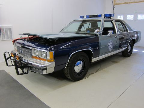 1991 Ford LTD Crown Victoria - This 1991 Ford Crown Victoria LTD police car, seen with its hood open, features a push bumper and a light bar.