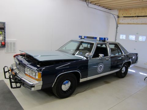 1991 Ford LTD Crown Victoria - 1991 Ford Crown Victoria LTD police car with its hood open, parked indoors.