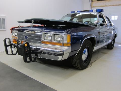 1991 Ford LTD Crown Victoria - Front view of a 1991 Ford Crown Victoria LTD police car with its hood open and emergency lights on top.