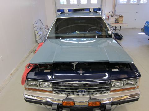 1991 Ford LTD Crown Victoria - Front view of a police car with its hood open, revealing the engine bay and a prominent Ford grille.