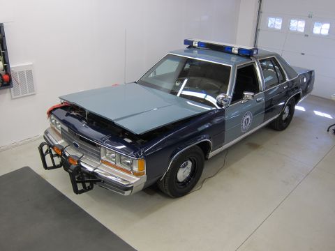 1991 Ford LTD Crown Victoria - Police car with hood open, parked indoors with a light bar on the roof.