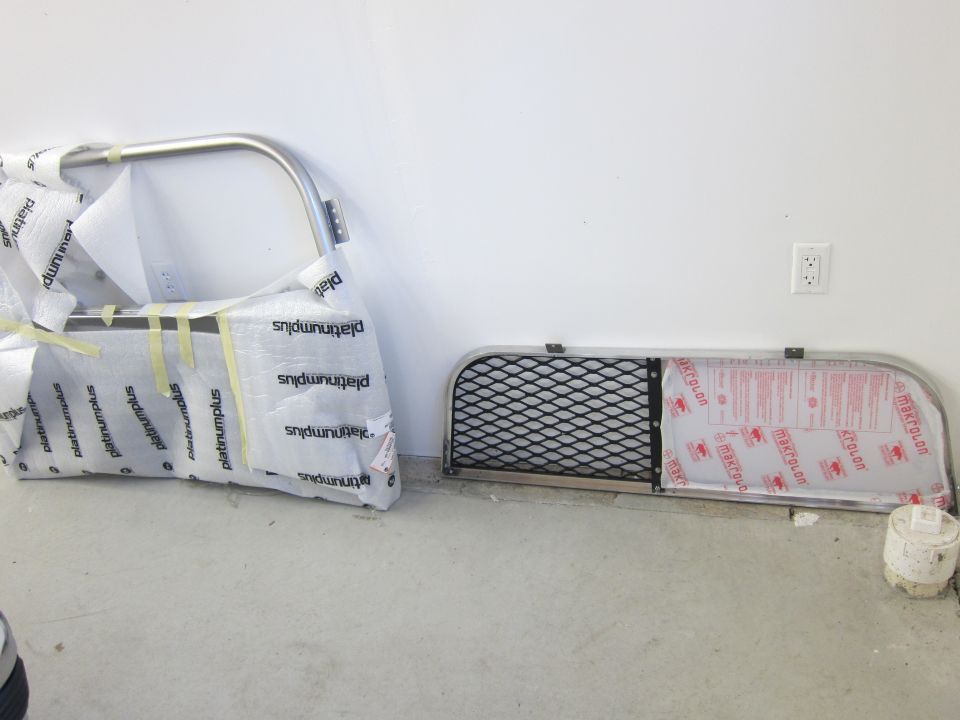 Two vehicle grille guards wrapped in protective plastic, one with a mesh insert