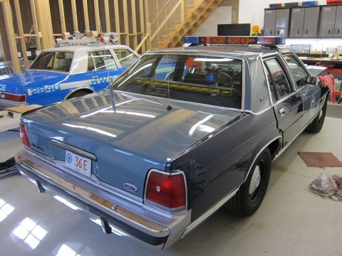 1991 Ford LTD Crown Victoria - A 1991 Ford Crown Victoria LTD police car is parked in a garage next to another police vehicle.