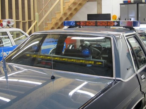 1991 Ford LTD Crown Victoria - Interior view of a police car's light bar and equipment, with another vehicle in the background.