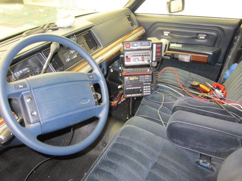 1991 Ford LTD Crown Victoria - The interior of a car is shown with a dashboard, steering wheel, and a stack of radio equipment installed on the center console.