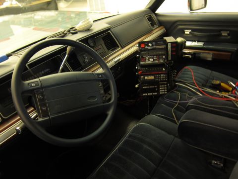 1991 Ford LTD Crown Victoria - Interior view of a car's dashboard and seats, multiple stacked radio units and visible wiring.