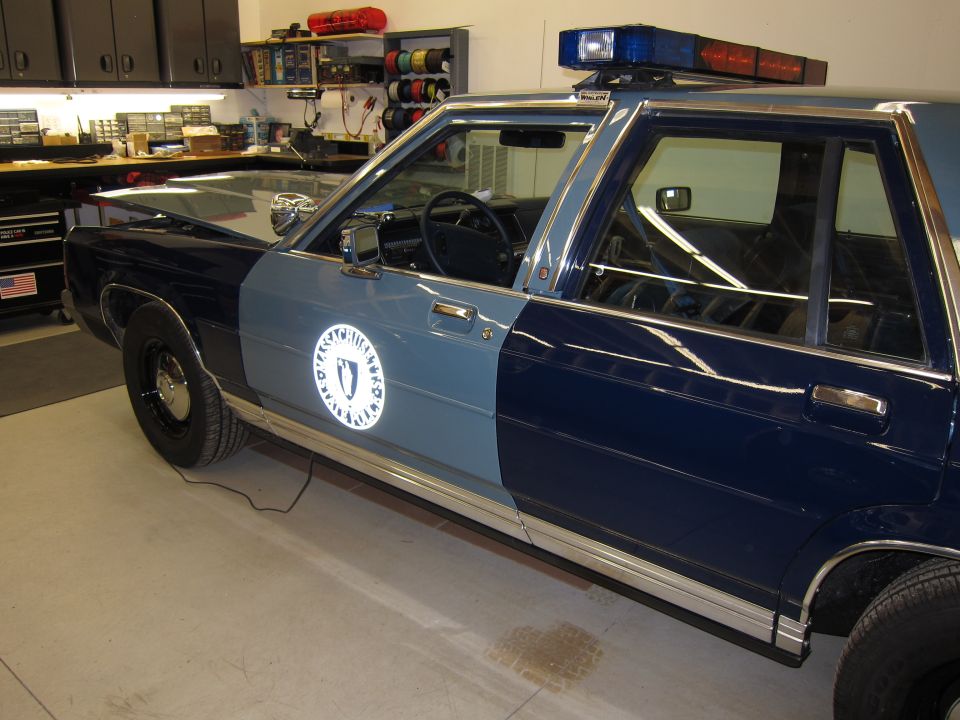 Police car with Massachusetts seal on door, light bar on roof
