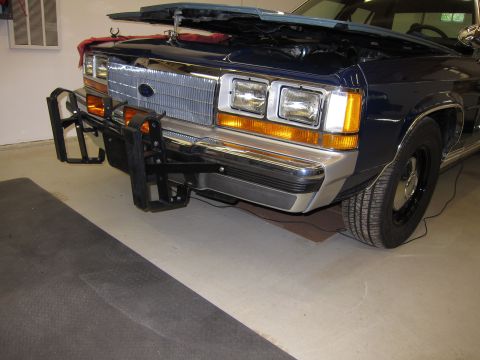 1991 Ford LTD Crown Victoria - Front view of a dark blue Ford Crown Victoria with a push bar and open hood.