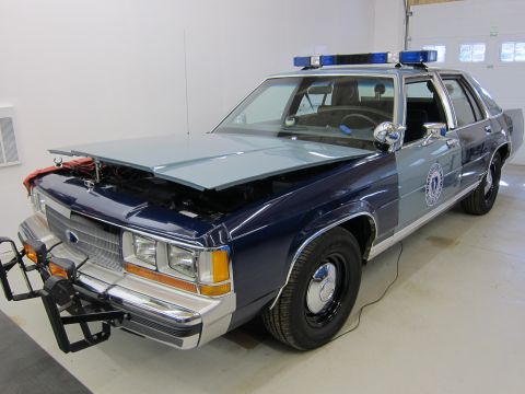 1991 Ford LTD Crown Victoria - Police car with hood open, revealing the engine compartment. It has a light bar on the roof.