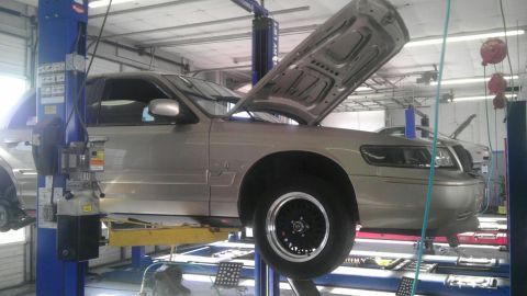 2000 Mercury Grand Marquis - Silver 2000 Mercury Grand Marquis on a car lift with its hood open, undergoing service.