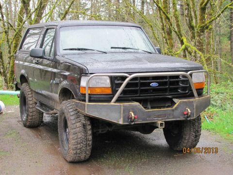 1989 Ford Bronco - This Ford Bronco features a custom front bumper and brush guard, seen here on a muddy road.