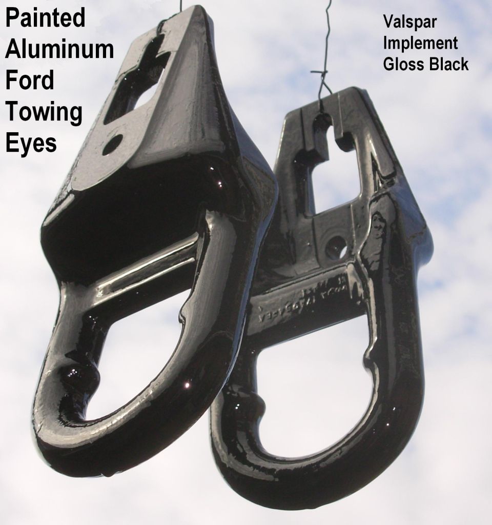 Two gloss-black painted aluminum Ford towing eyes hanging on wire