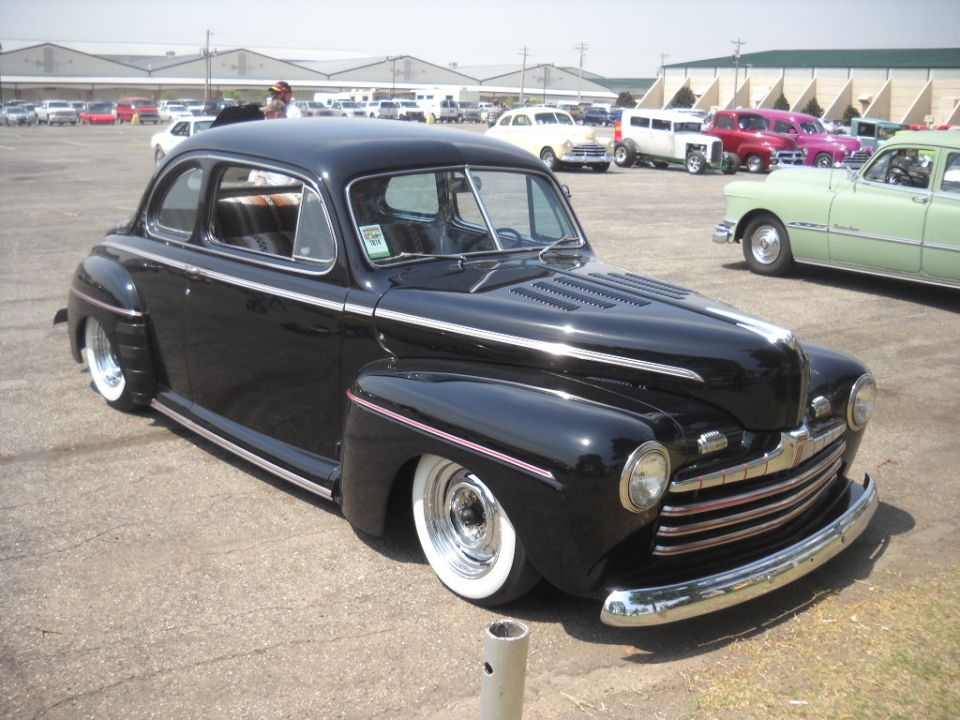 Black hot rod coupe with whitewall tires and chrome grille, parked outdoors