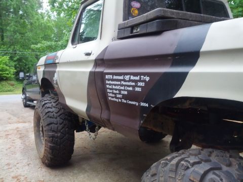 1979 Ford F-150 - Side view of a lifted 1979 Ford F-150 pickup truck with camouflage paint and off-road tires.