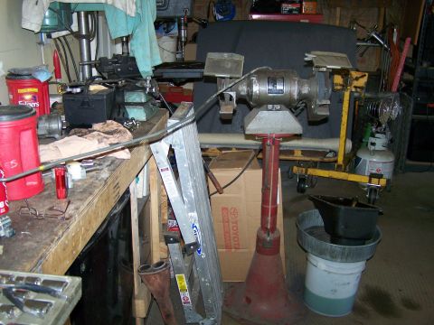 1988 Suzuki Samurai - A cluttered workshop scene displays various tools and machinery, including a drill press and a grinder.