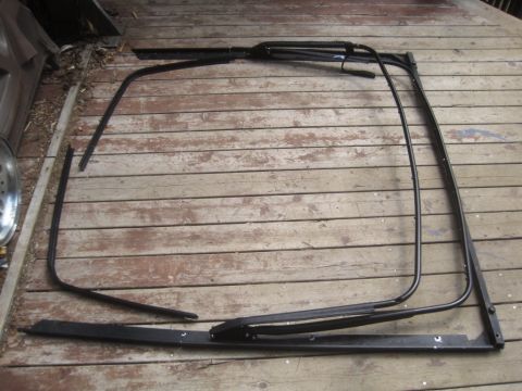 1993 Ford Bronco - Disassembled soft top frame components are shown laid out on a weathered wooden surface.