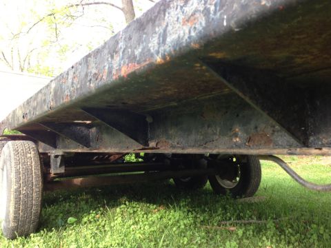 1989 Ford Bronco - The underside of a trailer shows significant rust and wear on its structural components.