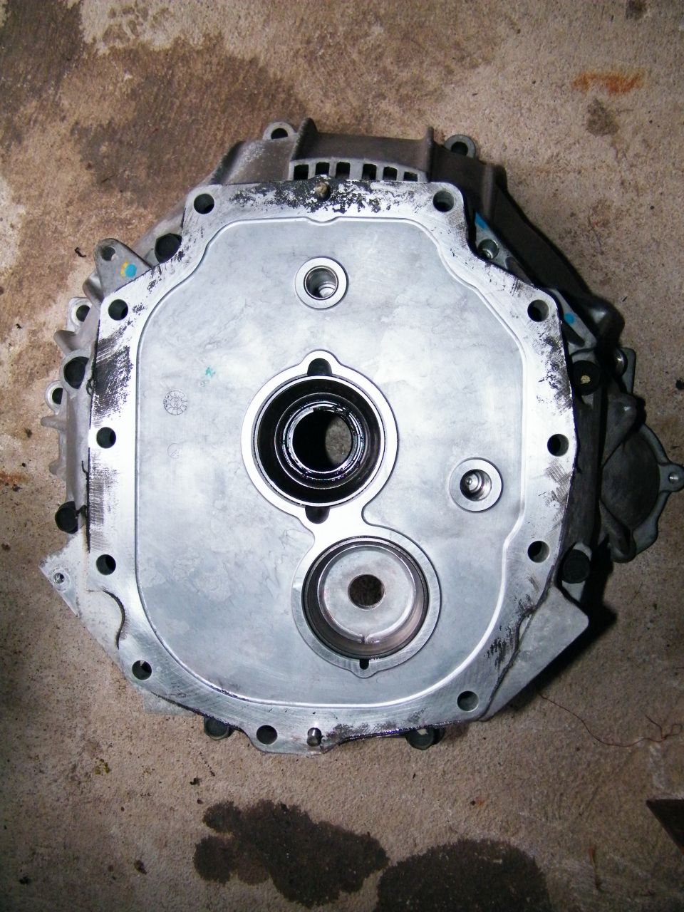 Close-up of a metal transmission component with circular openings and bolt holes