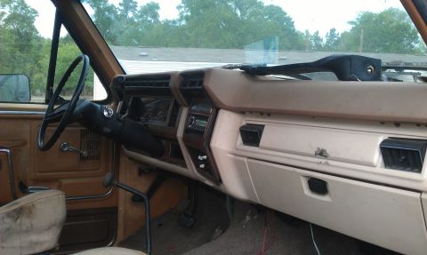 1982 Ford Bronco - The interior of the vehicle shows a tan dashboard with a radio and air vents.