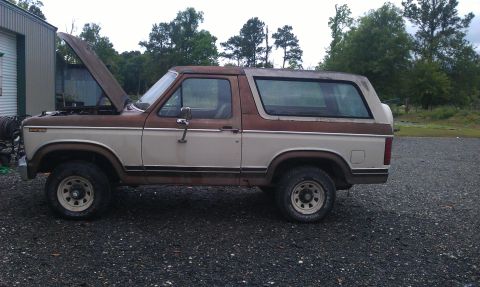 1982 Ford Bronco - This two-tone Ford Bronco sits on a gravel lot with its hood ajar.