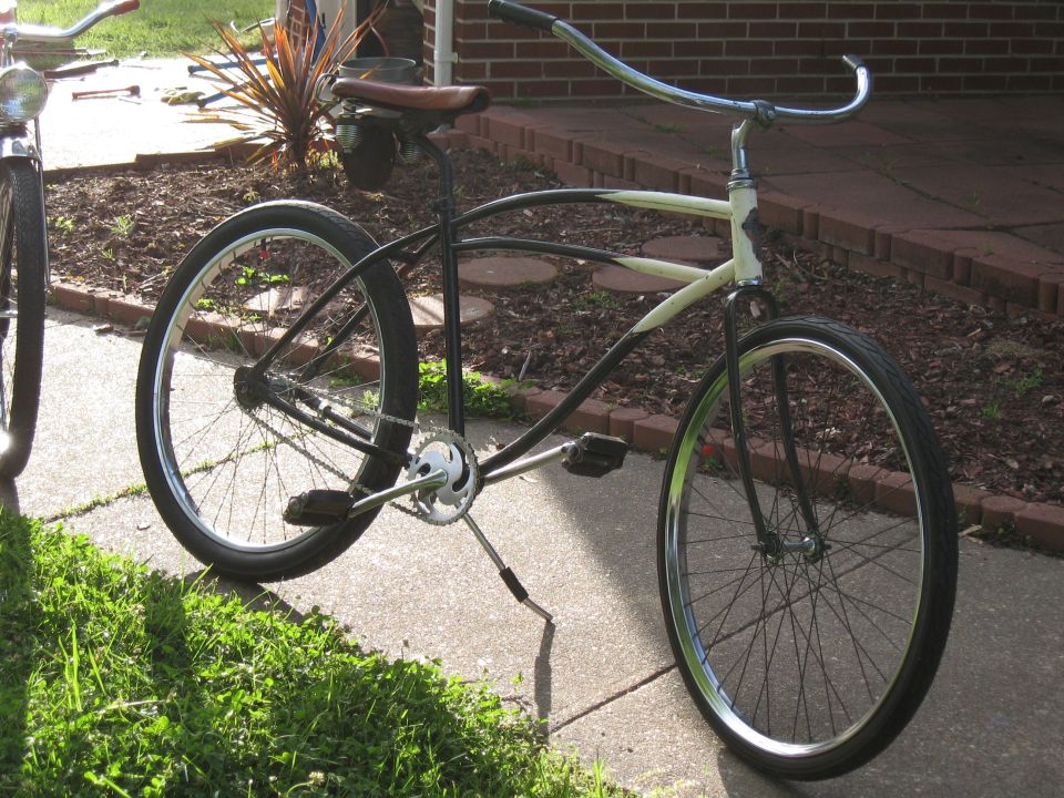 Side view of a black and cream cruiser bicycle with chrome handlebars