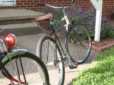 1994 Ford Bronco - A close-up view of two bicycles parked on a paved walkway near a brick building and flowering plants.
