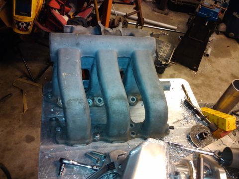 1995 Ford Probe - Intake manifold shown on a workbench, surrounded by tools and metal shavings.