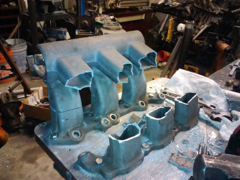 1995 Ford Probe - Aluminum intake manifold with ports cut open, on a workbench with tools and debris.