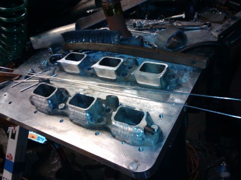 1995 Ford Probe - Close-up of an engine intake manifold part on a workbench, with tools and metal rods visible.