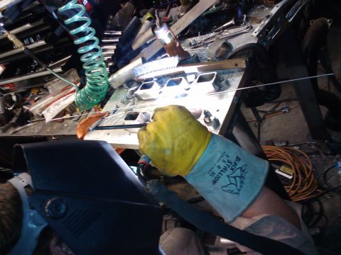 1995 Ford Probe - A person wearing a welding mask and yellow gloves works on a car part in a cluttered garage.