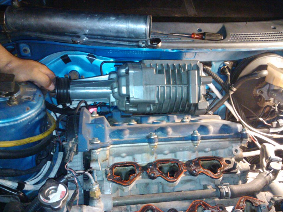 hand installing supercharger onto car engine