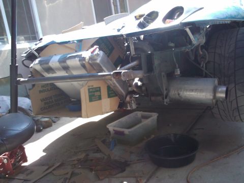 1995 Ford Probe - The rear of a car is disassembled, with parts and boxes scattered on the ground.