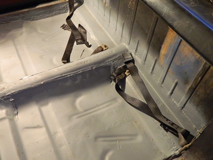 1962 Ford Ranchero - The interior floor of a vehicle, showing seatbelt anchors and gray painted metal surfaces.