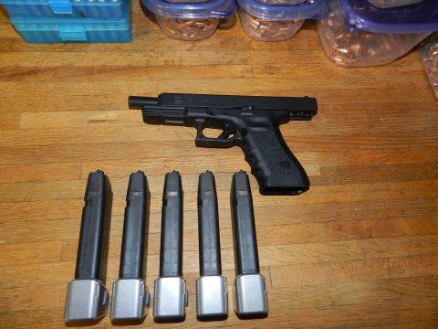 1996 Ford Bronco - Glock pistol and extended magazines laid out with ammunition boxes on a wooden table.