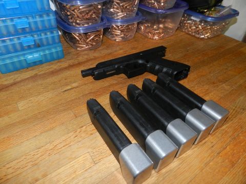 1996 Ford Bronco - A handgun and multiple loaded magazines are laid out on a wooden table next to containers of ammunition.