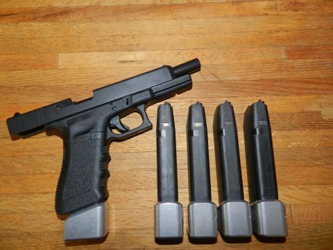 1996 Ford Bronco - A black pistol is displayed with four spare magazines on a wooden table.