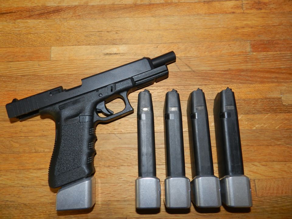 Black pistol with four magazines on a wooden surface
