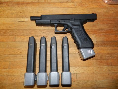 1996 Ford Bronco - A black pistol with an extended magazine and four additional magazines are laid out on a wooden surface.