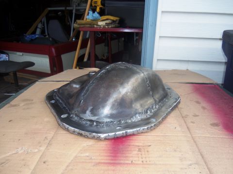 1968 Ford Bronco - A freshly welded differential cover sits on a cardboard surface in a garage setting.