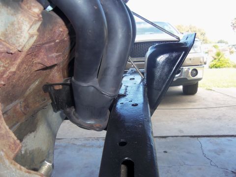 1968 Ford Bronco - Focus on the exhaust manifold and frame, with a tan truck visible in the background.