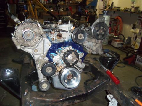 1968 Ford Bronco - Engine assembly with blue painted block, alternator, and pulleys is mounted on a metal frame in a workshop.